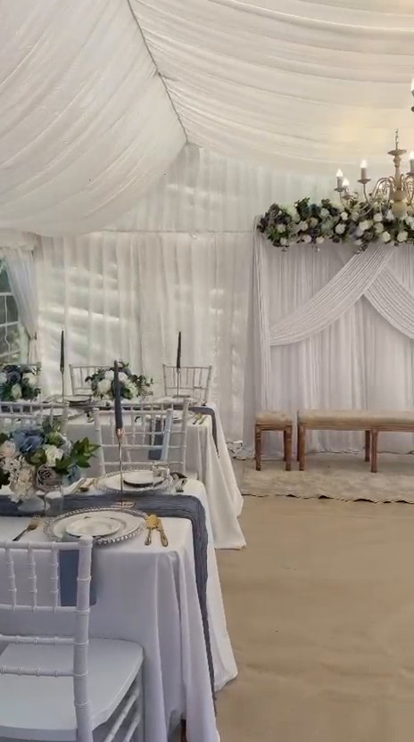 Nikkah marquee reception setup showing ceremony stage and dressed dining tables with chandelier lighting
